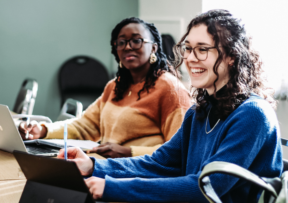 2 students smile while sitting in class