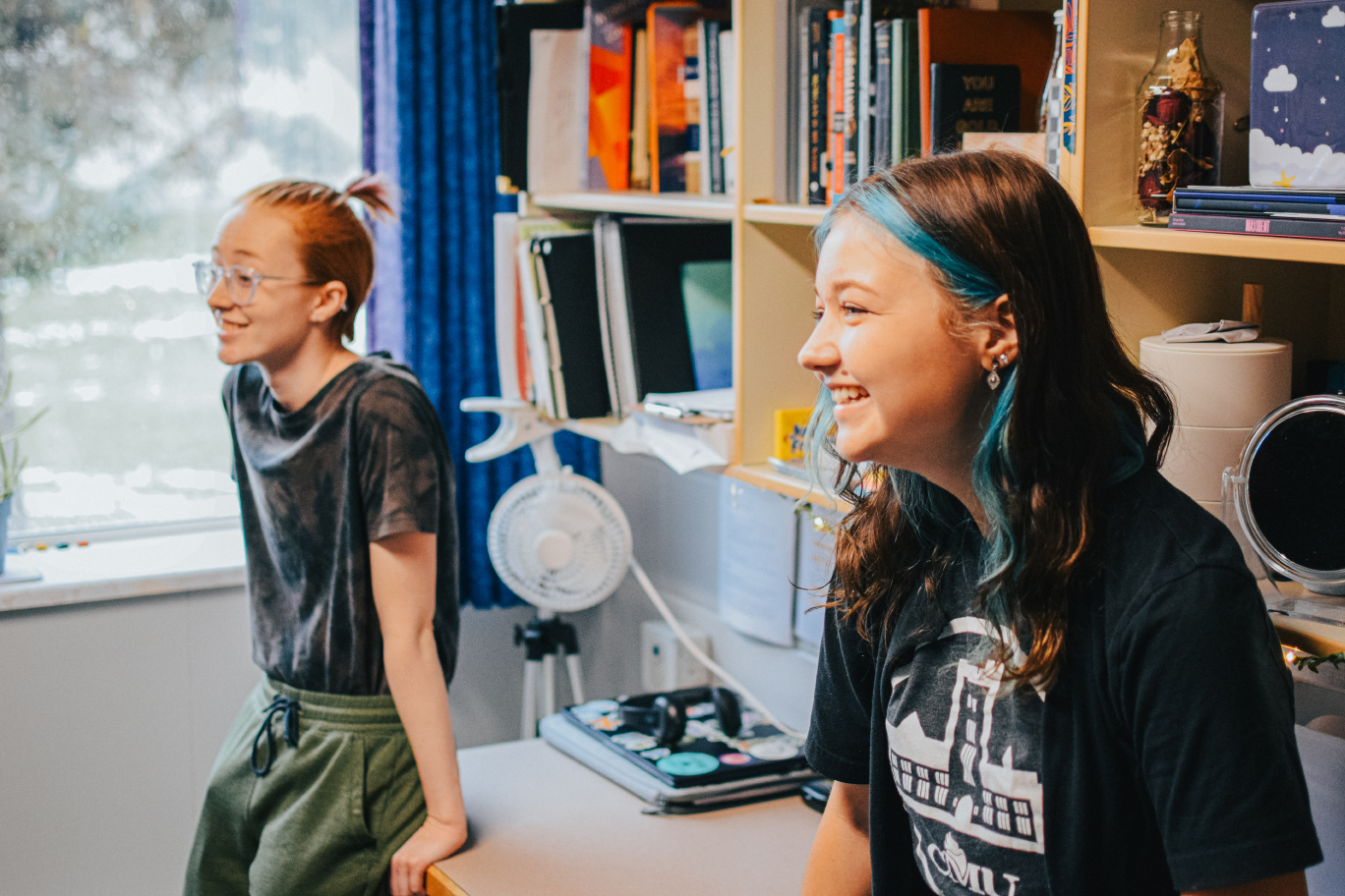 2 students smile in a dorm room