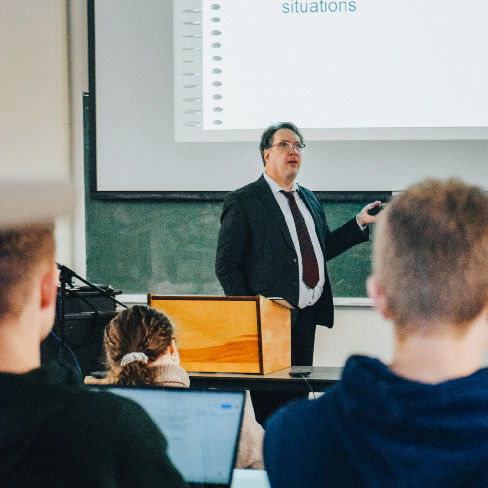 A professor teaches in front of a group of students